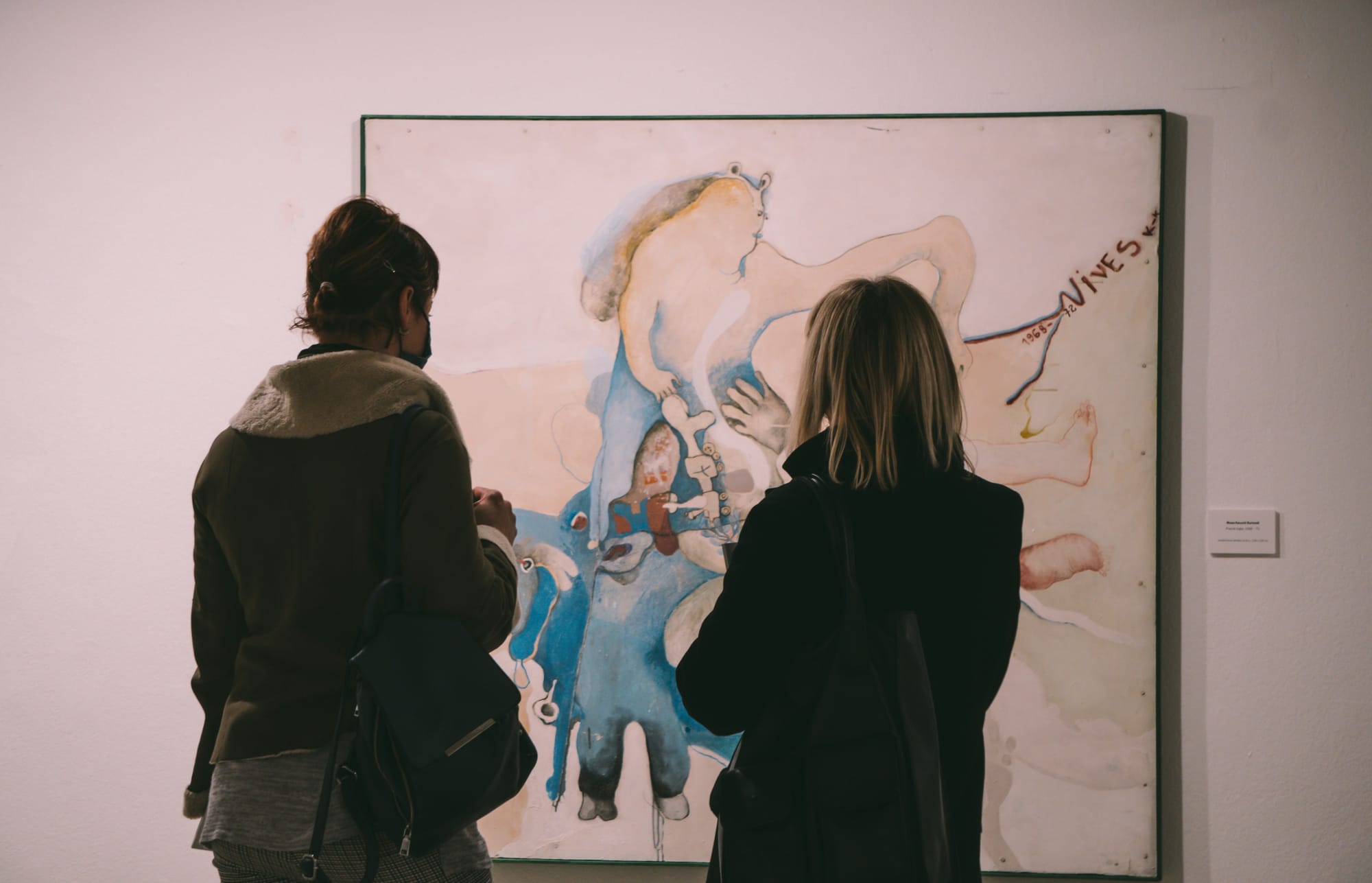 A gallery visitor admiring a framed painting, illustrating the disconnect between rising art values and artist compensation.