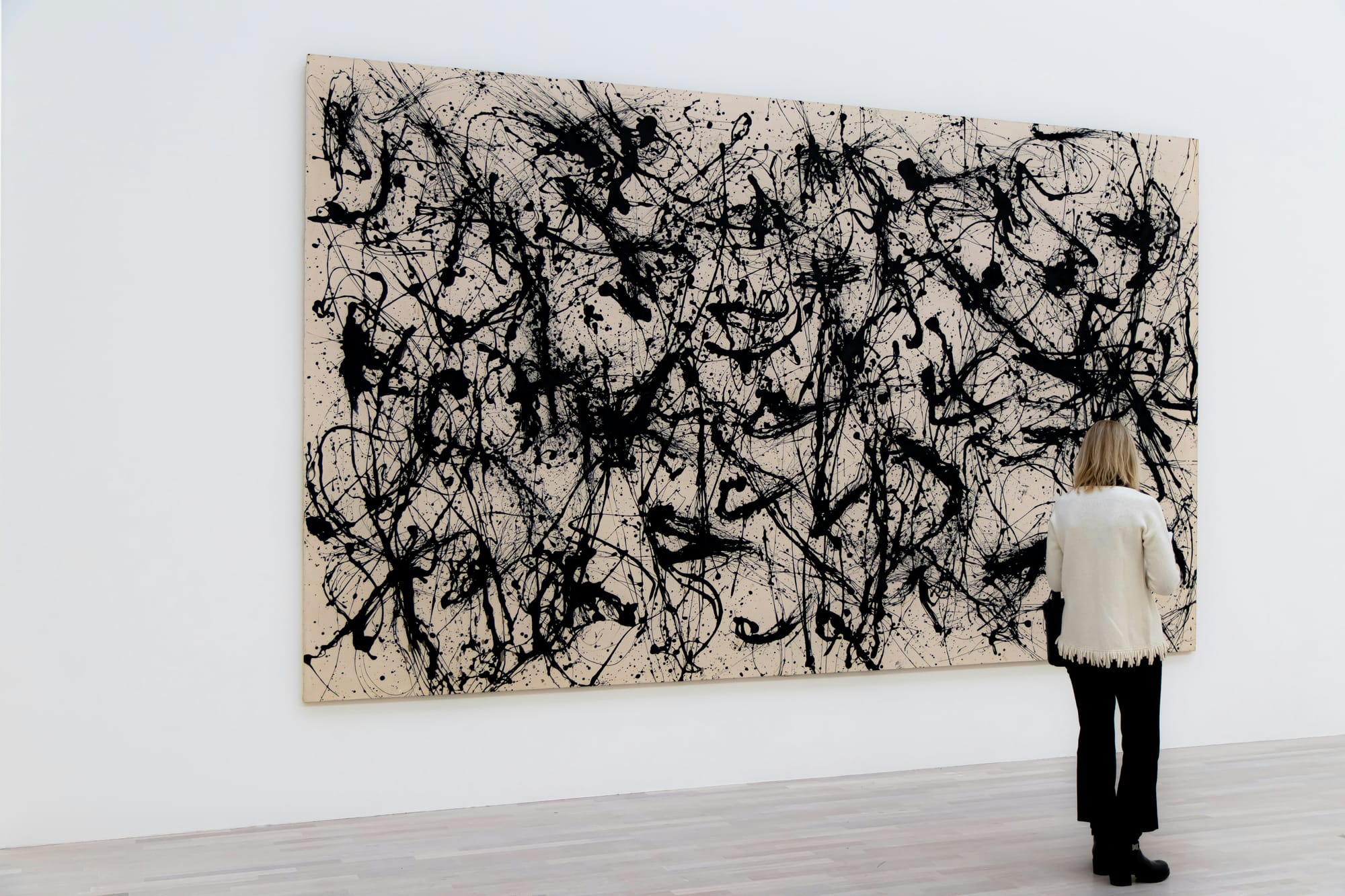A gallery visitor admiring a framed painting, illustrating the disconnect between rising art values and artist compensation.