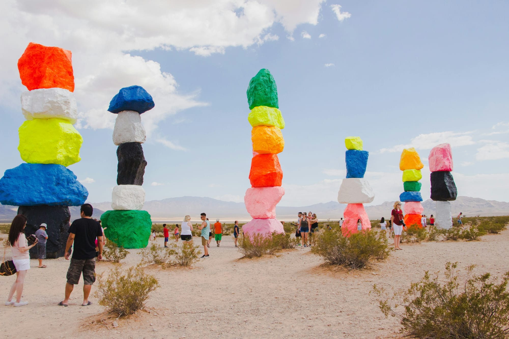 A group of people gathered in awe around a large art installation in the middle of a desert.