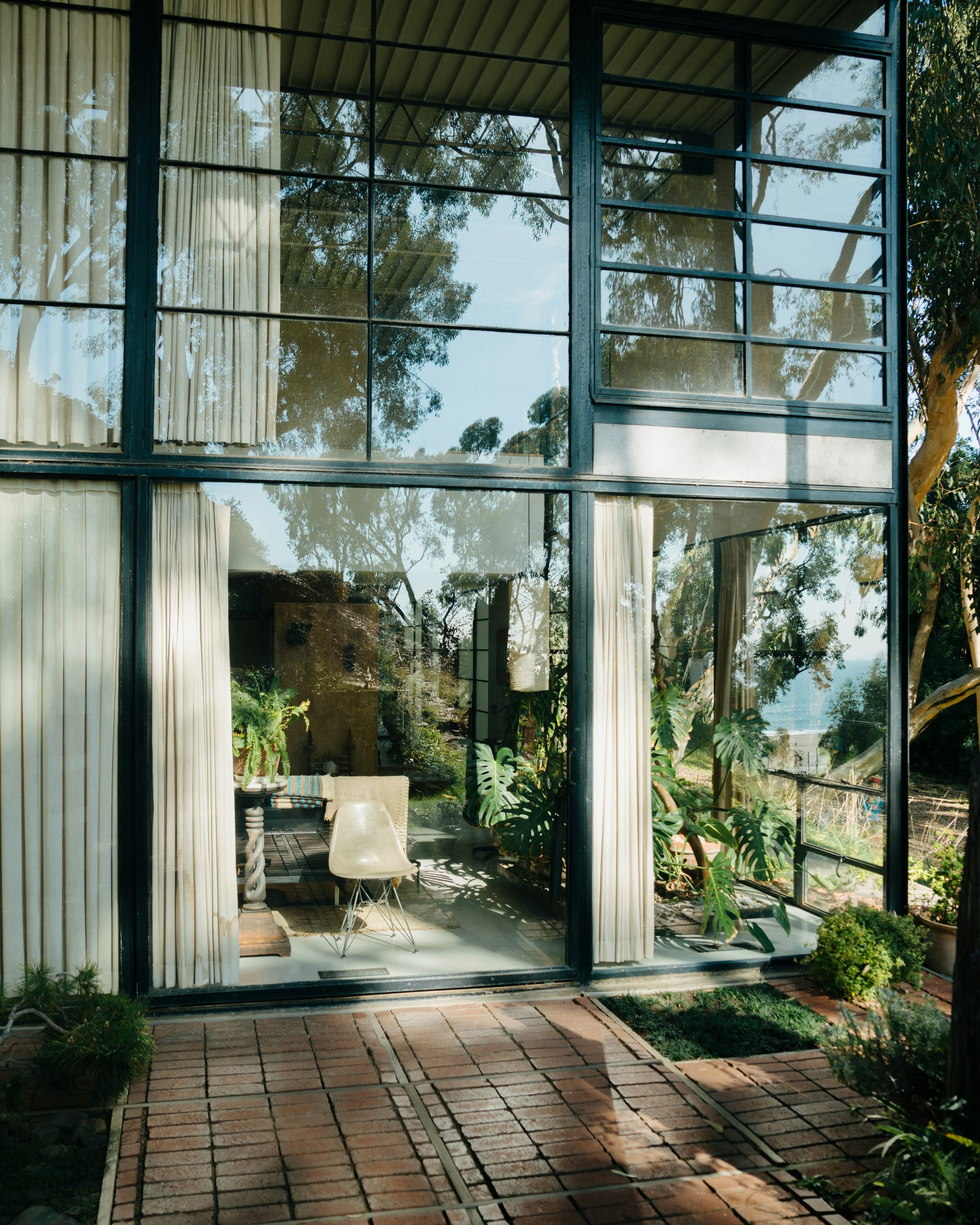 Exterior view of the Eames House looking through a large glass window into the downstairs room