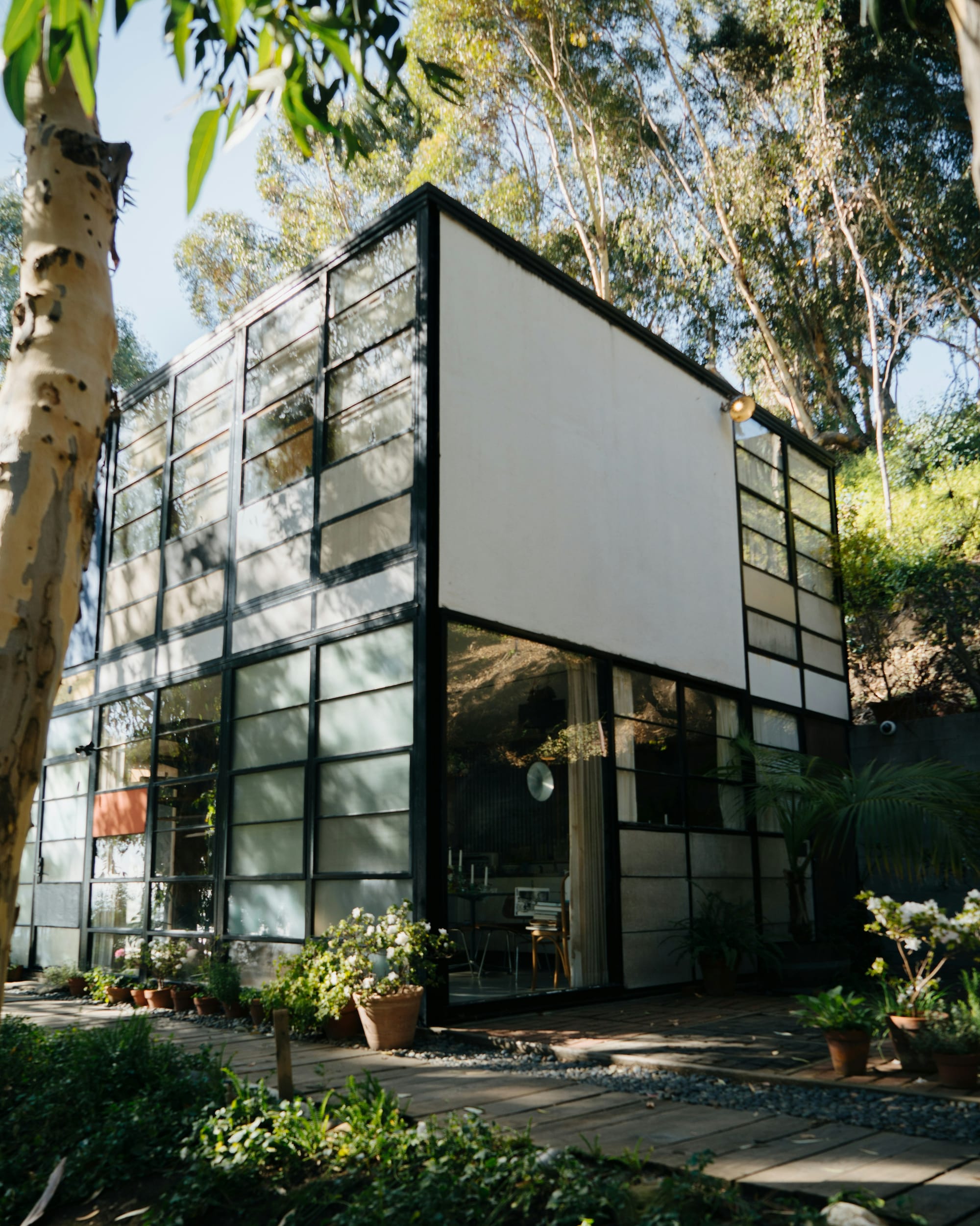 Mid-century modern Charles and Ray Eames House with steel frame, colorful panels, and glass walls, nestled in the hillside of California’s Pacific Palisades after surviving wildfires