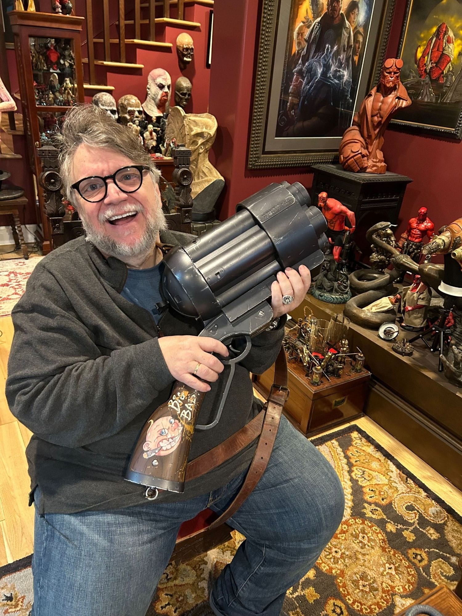 Guillermo del Toro holding the oversized “Big Baby” shotgun prop from Hellboy, part of his Bleak House collection heading to auction