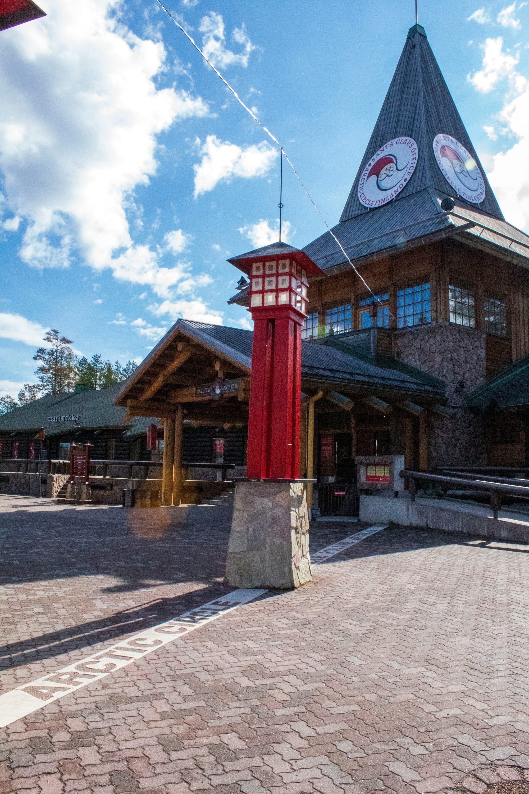 Santa Claus Village in Rovaniemi on the Arctic Circle with log cabins and signage