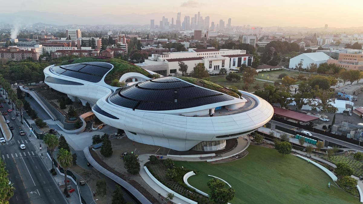 A sweeping aerial view of the futuristic, curved Lucas Museum of Narrative Art rising above Los Angeles’s Exposition Park.