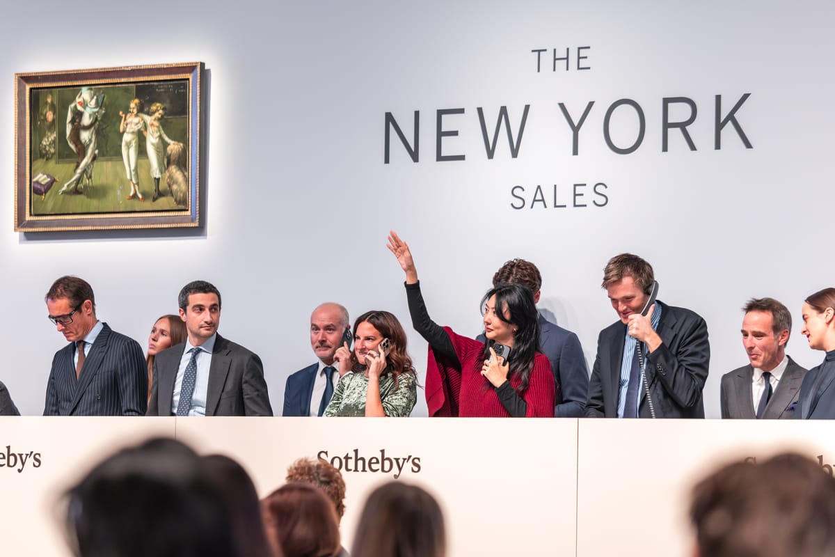 Crowded Sotheby’s salesroom in New York with bidders raising paddles as the auctioneer drives the price higher.