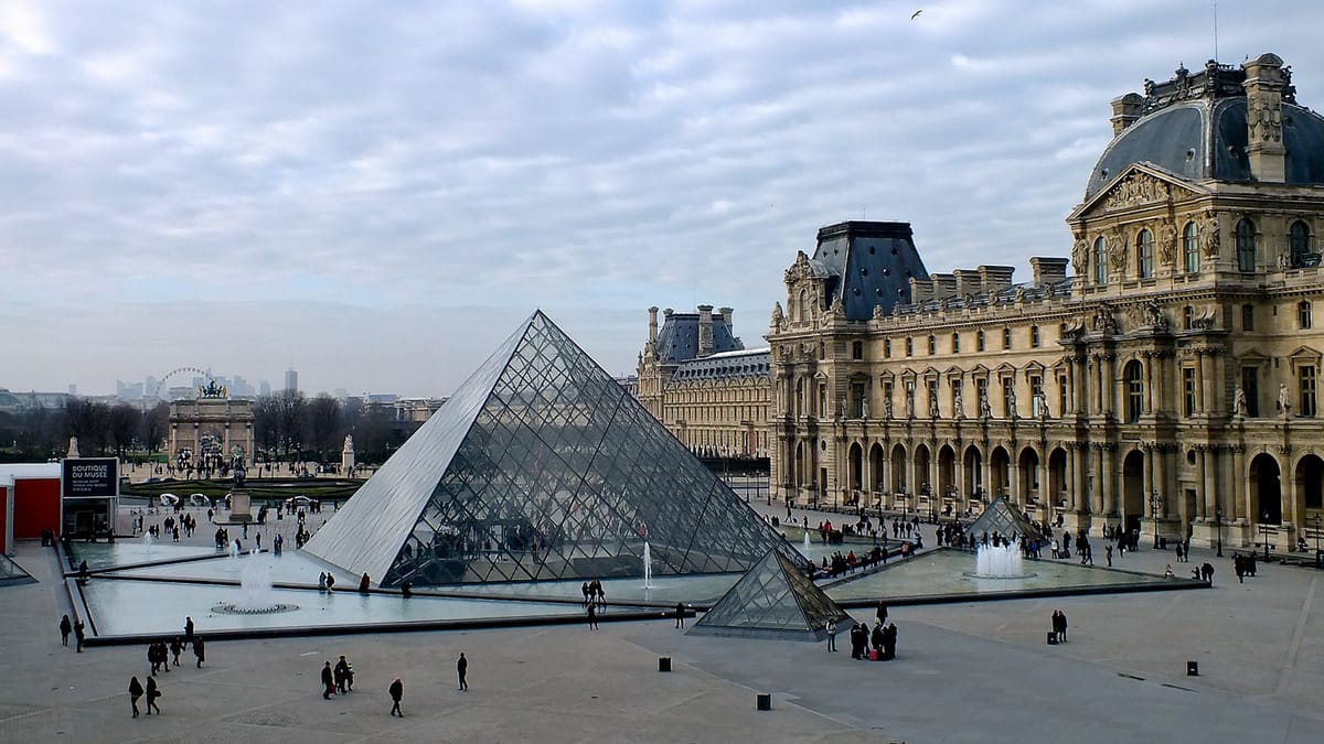 Visitors lining up beneath the Louvre pyramid on a cold day in Paris.