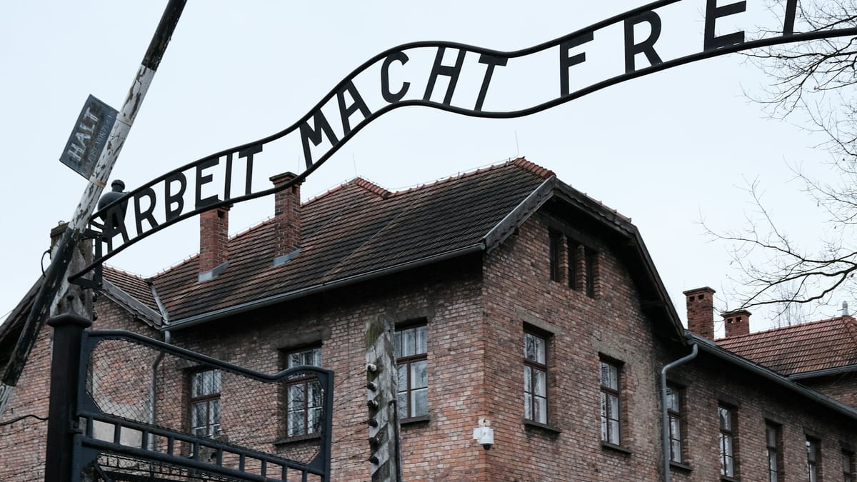 Guard facilities and barbed-wire fencing at concentration camp on a grey day.