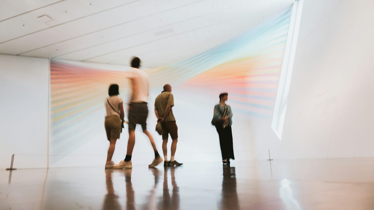 Curators and visitors attending a quiet preview inside a gallery ahead of a public exhibition opening.
