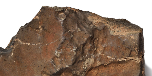 Close-up image of Martian meteorite NWA 16788 with visible glassy surface, displayed by Sotheby’s