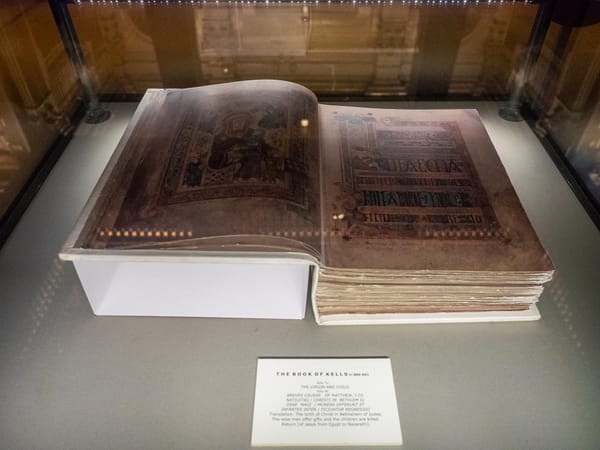 Illuminated page from the Book of Kells with intricate interlace and display capitals, photographed at Trinity College Dublin