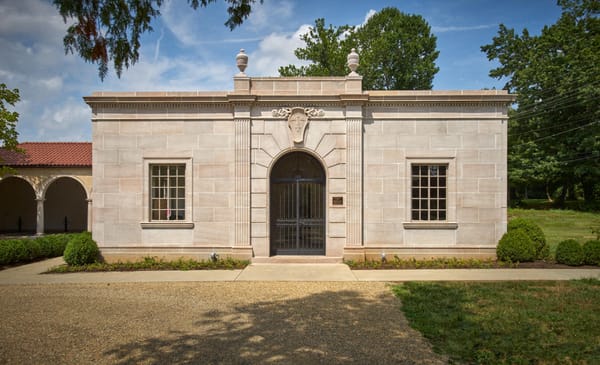 Exterior view of the Candoro Marble Building in Knoxville, Tennessee, showing its Tennessee pink marble façade, arched windows, and tree-lined entrance drive
