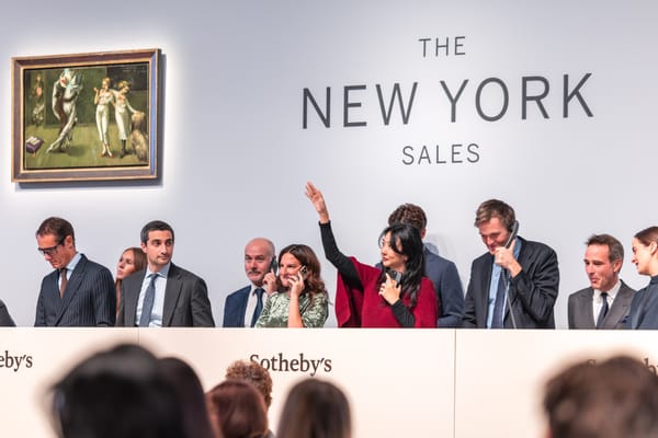 Crowded Sotheby’s salesroom in New York with bidders raising paddles as the auctioneer drives the price higher.
