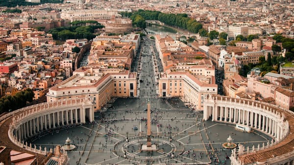 Aerial view of the Vatican, with St Peter’s Basilica and surrounding courtyards set against the dense urban fabric of Rome.