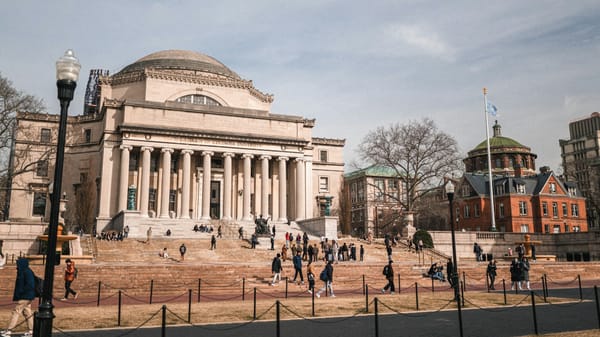 Facade of a historic University of New York building with stone columns and wide steps.
