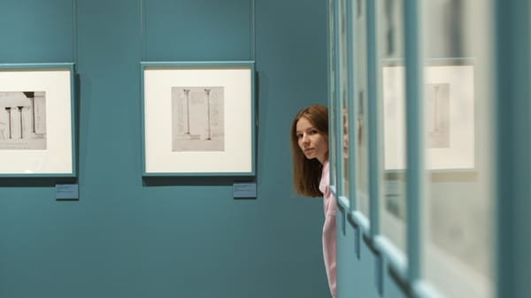 A visitor using a phone to navigate an art gallery filled with contemporary works.